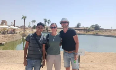 Wael egittologo e proprietario di Egitto Unico con due turisti durante l’escursione di 2 giorni a Luxor da Marsa Alam davanti al lago sacro del Tempio di Karnak