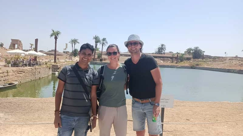 Wael egittologo e proprietario di Egitto Unico con due turisti durante l’escursione di 2 giorni a Luxor da Marsa Alam davanti al lago sacro del Tempio di Karnak