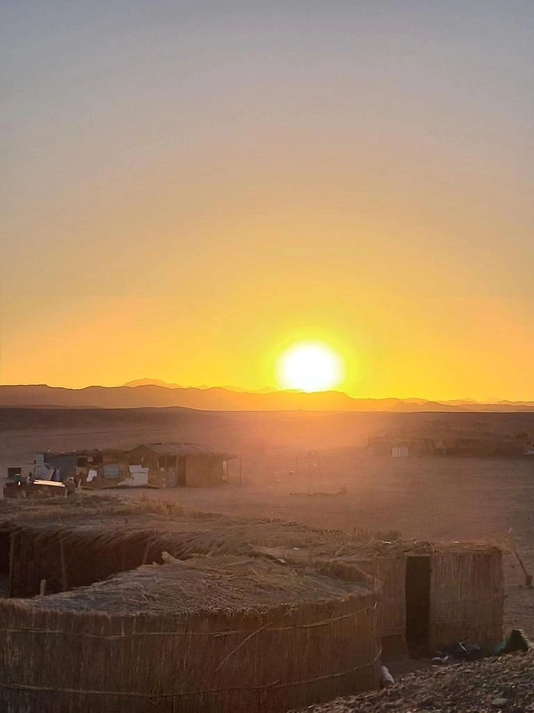 Il sole tramonta dietro le montagne nel deserto di Marsa Alam con vista sul campo beduino dell’escursione di Egitto Unico