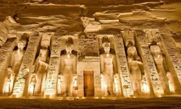 Facciata del Tempio di Nefertari ad Abu Simbel illuminato di notte con statue scolpite nella roccia durante l'escursione da Marsa Alam ad Assuan