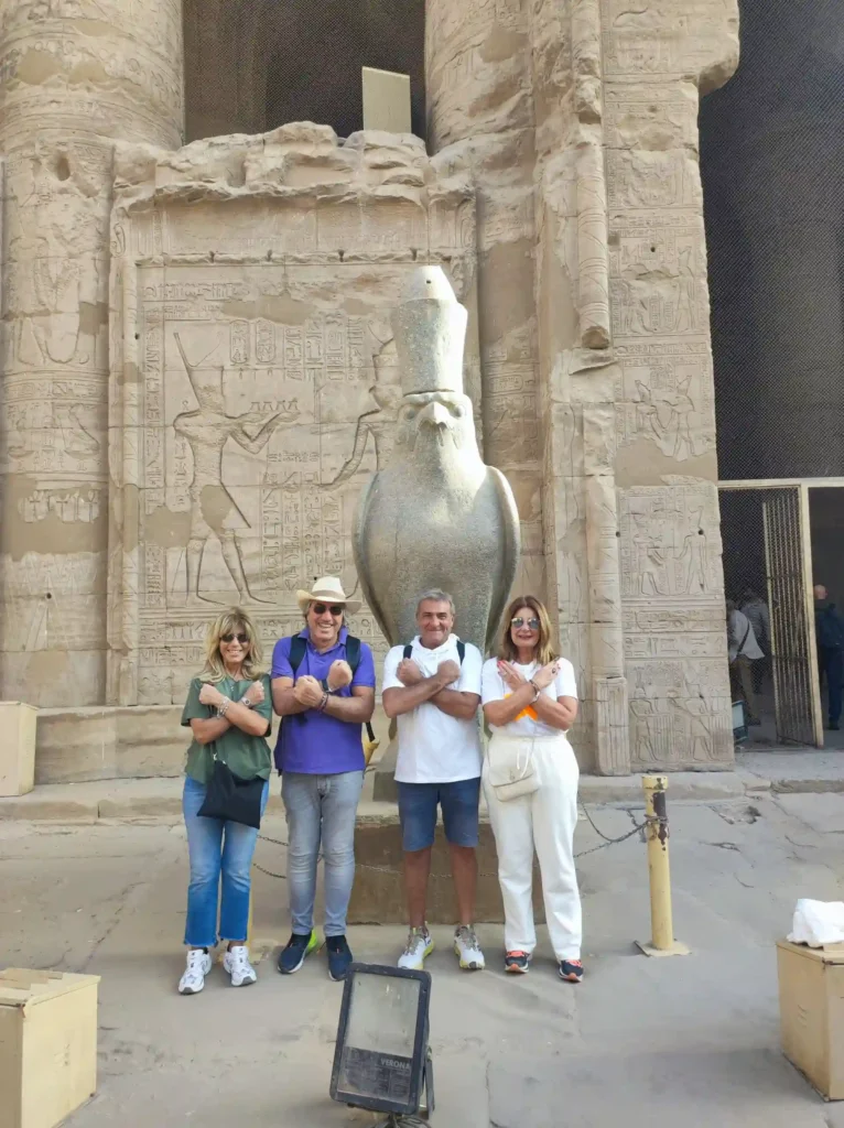 Gruppo di turisti davanti alla statua del dio Horus al Tempio di Edfu durante il tour in giornata a Edfu e Kom Ombo con partenza da Luxor
