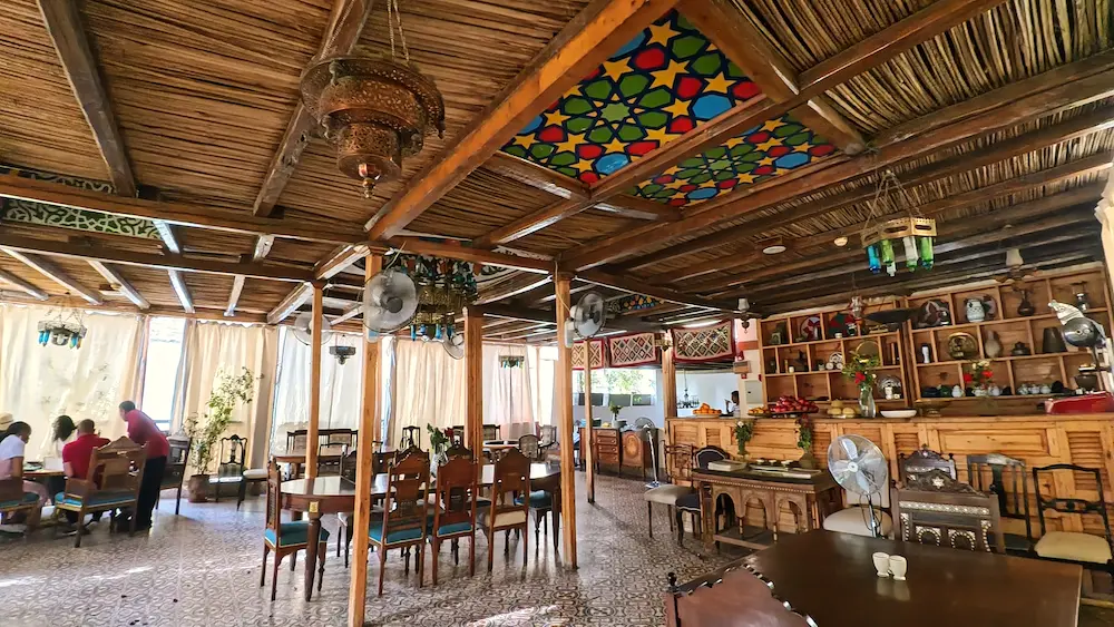 Interno del Sofra Restaurant a Luxor con soffitto in legno, lampadari tradizionali in metallo, vetrate colorate e tavoli in stile arabo egiziano